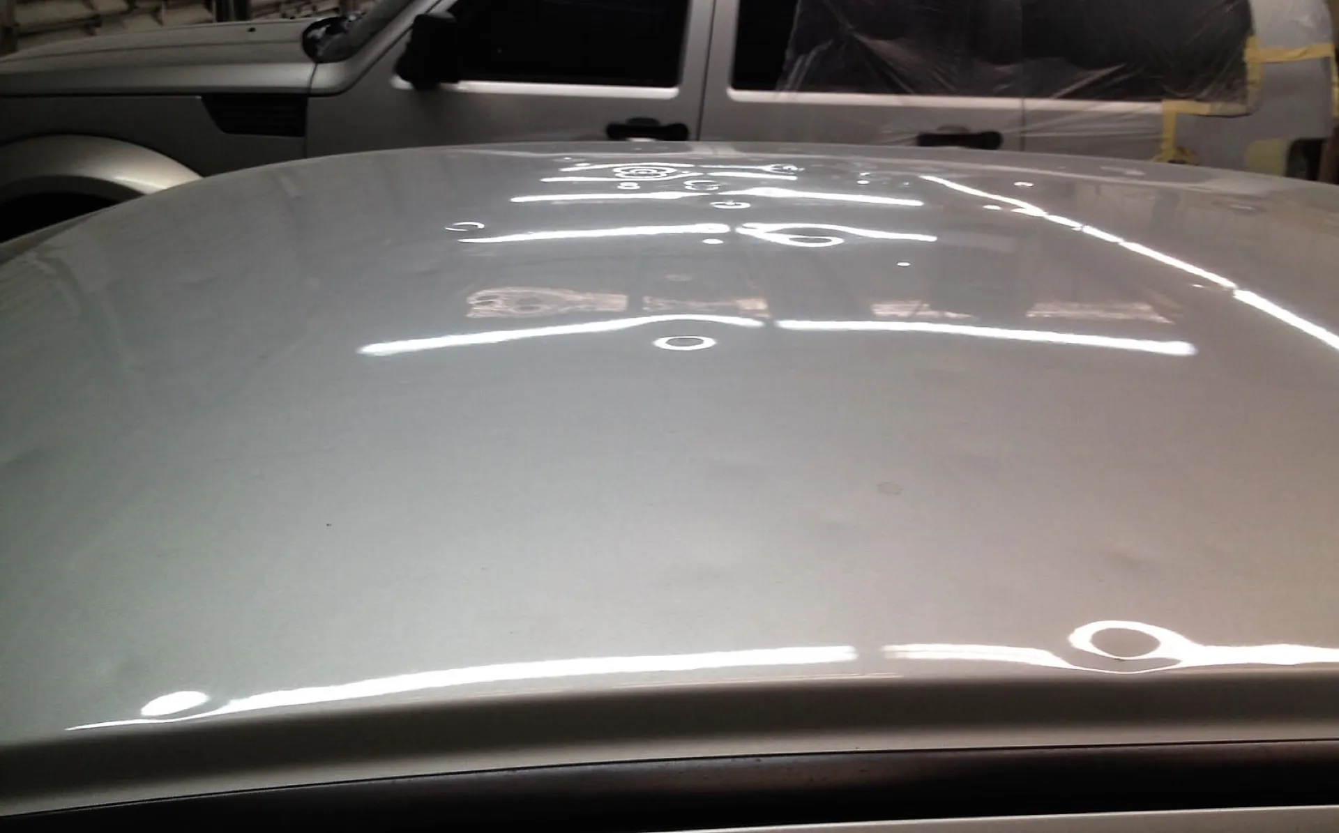 Hail-dented car roof being inspected